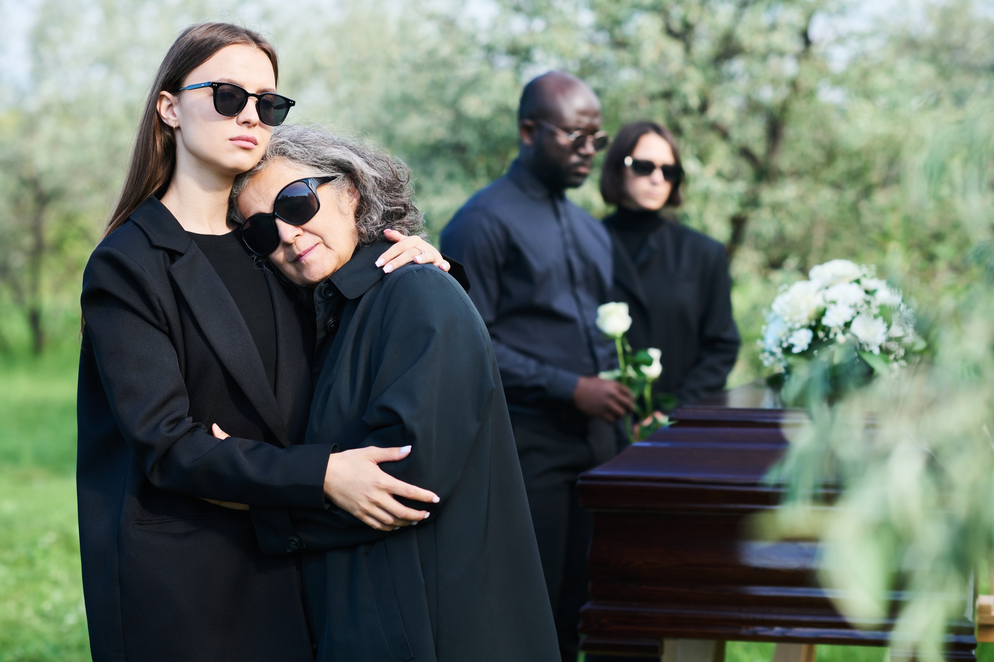 Mature grieving woman in black attire keeping head on shoulder of her daughter